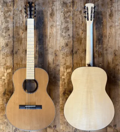 Front and back views of a light wood acoustic guitar on a rustic wooden wall.